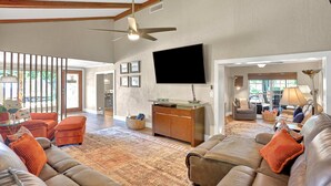 A spacious living room with a large leather sofa, a television mounted on the wall, and a wooden ceiling. - Riverfront retreat with pool spa outdoor kitchen firepit dock sauna and games (Tampa)