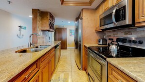 A kitchen with wooden cabinets, stainless steel appliances, and a granite countertop. - Waterfront condo with heated pool hot tub central AC and WD snowbird friendly (Indian Shores)
