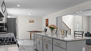 A modern kitchen with grey cabinets, a marble countertop, and a gas stove. - Large house in pleasant Poconos with HotTub PAC-MAN, Fooseball, PingPong & More! (tobyhana)