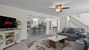A modern living room with a grey sofa, a coffee table, and a TV displaying 'NETFLIX'. - Large house in pleasant Poconos with HotTub PAC-MAN, Fooseball, PingPong & More! (tobyhana)
