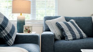 A cozy living room with a blue sofa, a matching armchair, a lamp, and a decorative mirror on the wall. - Large house in pleasant Poconos with HotTub PAC-MAN, Fooseball, PingPong & More! (tobyhana)