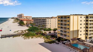 Ett hotell vid stranden med flera balkonger, en swimmingpool och utsikt över stranden.