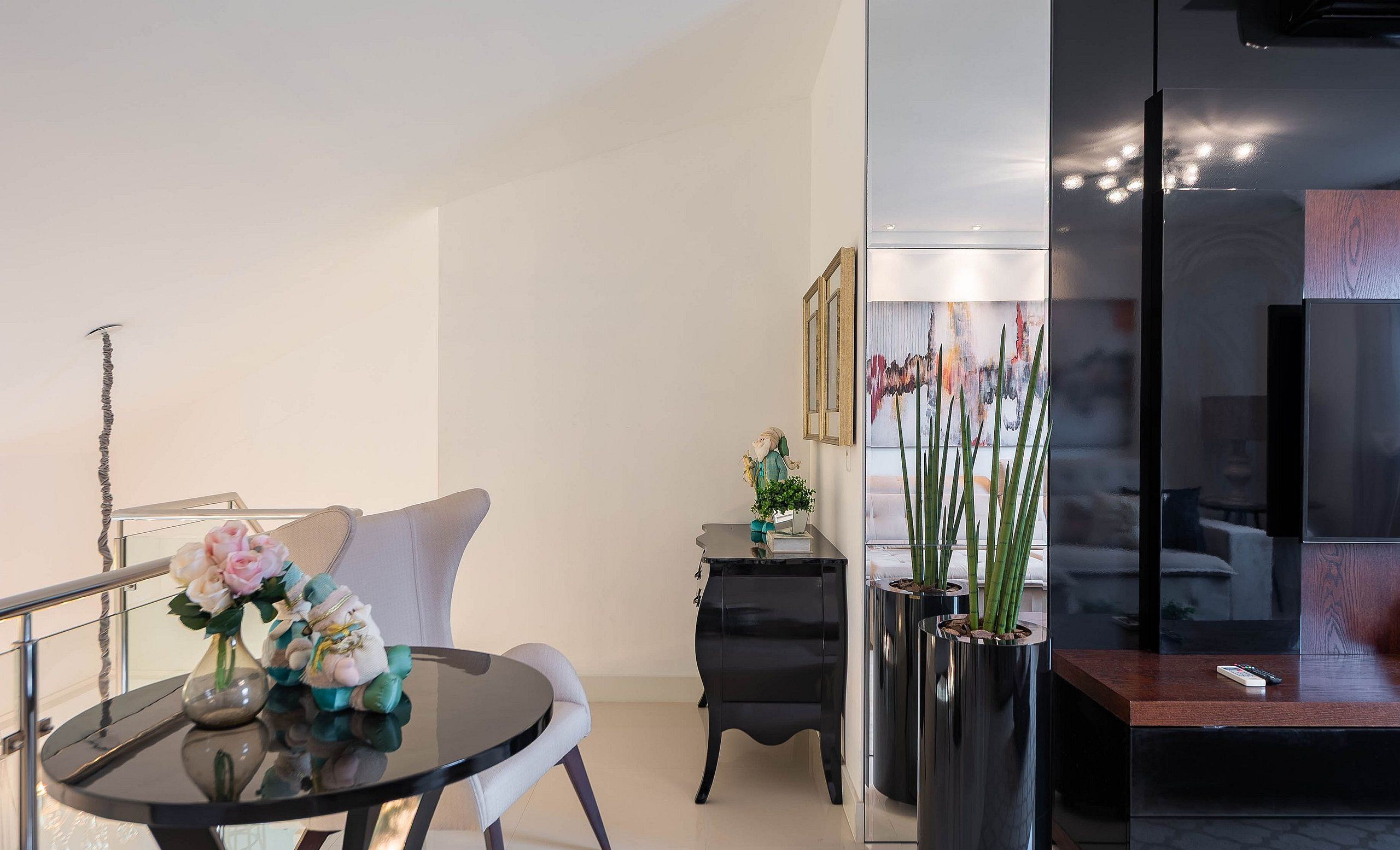 Una sala de estar moderna con una mesa de vidrio, un sofá, un mueble negro y un cuadro en la pared.