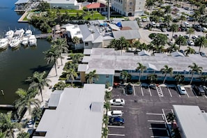 An aerial view of a marina with boats docked, a parking lot, and buildings with a flat roof and palm trees. - 1st floor condo with private dock easy beach access heated pool and patio (Indian Shores)
