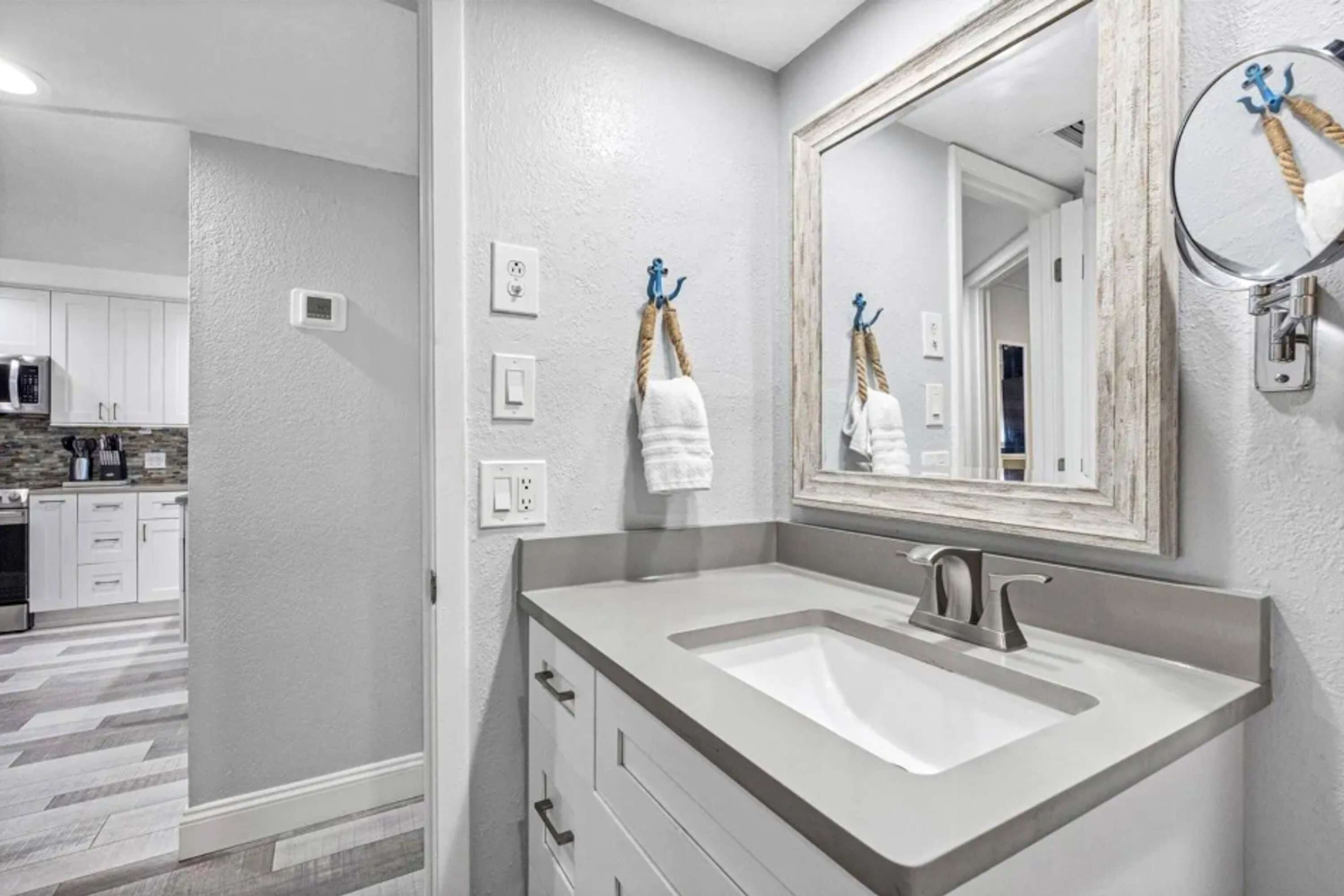 Un baño con un espejo grande, un lavabo y un perchero con toallas.