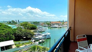 A balcony with a view of a marina, boats, and buildings. - Intracoastal view condo with pool hot tub and marina access walk to beach (Madeira Beach)