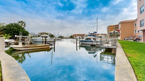 A marina with boats docked, a clear sky, and buildings in the background. - Intracoastal view condo with pool hot tub and marina access walk to beach (Madeira Beach)