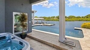 Una vasca idromassaggio e una piscina su un balcone con vista su un lago e delle case.
