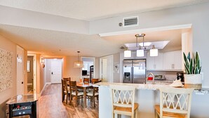 A modern kitchen with a central island, bar stools, and a dining area with chairs.