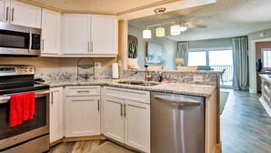 A modern kitchen with white cabinets, stainless steel appliances, and a granite countertop.