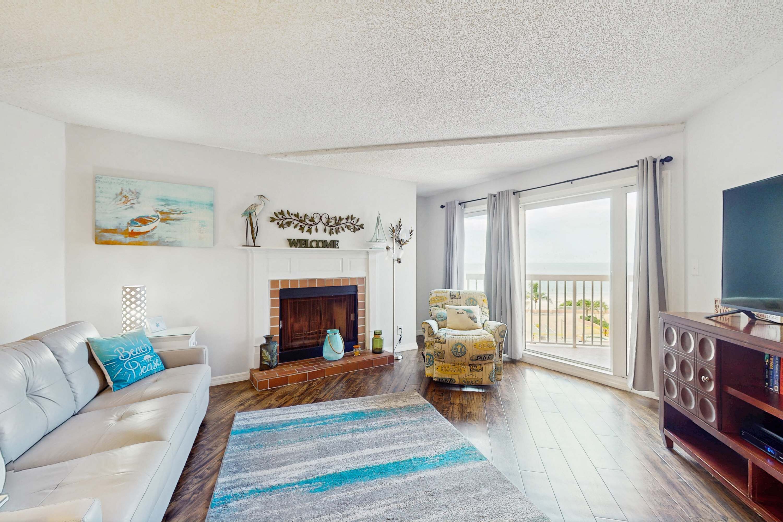 A living room with a fireplace, a sofa, a chair, and a TV stand.
