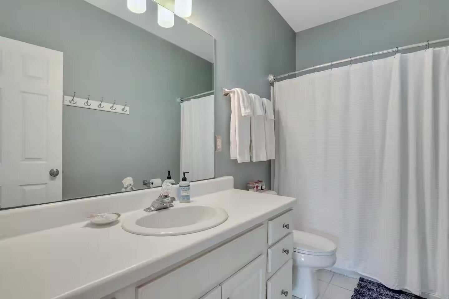 A bathroom with a white sink, a mirror, a toilet, and a shower curtain.