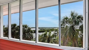 A window with a view of palm trees and a body of water. - Coral Cottage House in Pine Island (Weeki Wachee)
