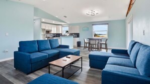 A modern living room with a blue sofa set, a coffee table, and a dining area with a table and chairs. - Coral Cottage House in Pine Island (Weeki Wachee)