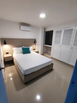 A bedroom with a bed, bedside tables, an air conditioner, a TV, and a wardrobe. - Em3-2g 4-bedroom Apartment in a Residential Area With air Conditioning and Wifi (Cartagena)