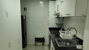 A kitchen with white cabinets, a black countertop, and a stainless steel sink. - Em3-2g 4-bedroom Apartment in a Residential Area With air Conditioning and Wifi (Cartagena)