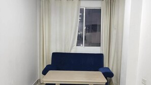A small, well-lit room with a blue sofa, a small table, and two blue ottomans. - Em3-2g 4-bedroom Apartment in a Residential Area With air Conditioning and Wifi (Cartagena)