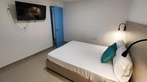 A bedroom with a bed, a TV mounted on the wall, a door, and an air conditioning unit. - Em3-2g 4-bedroom Apartment in a Residential Area With air Conditioning and Wifi (Cartagena)