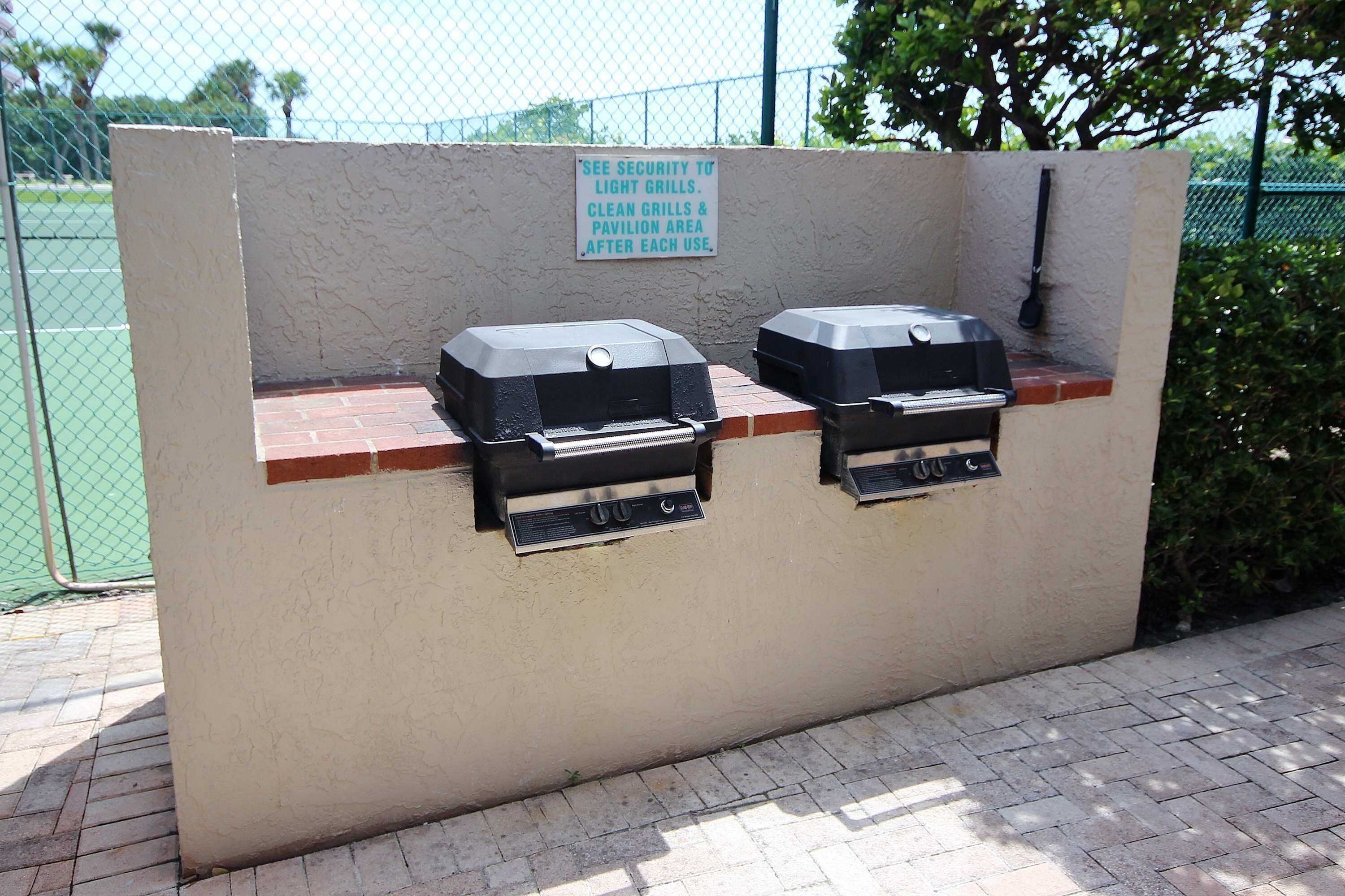 Un espace barbecue avec un panneau indiquant qu’il faut nettoyer les grils et la zone abritée après utilisation.