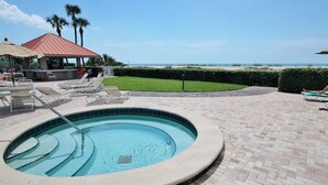 A swimming pool with lounge chairs and a view of the beach.