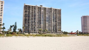 A high-rise hotel with multiple floors, a flat roof, and a beach view.