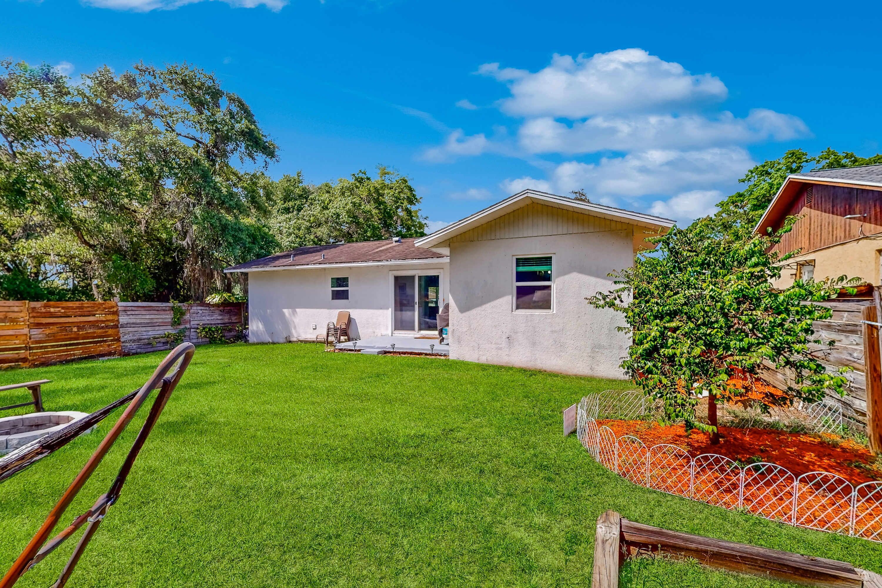 A single-story house with a well-maintained lawn, a patio with outdoor furniture, and a wooden fence.