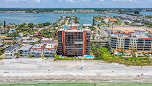Ein Hotel an der Küste mit mehreren Etagen, Blick auf den Strand und einem Yachthafen im Hintergrund.