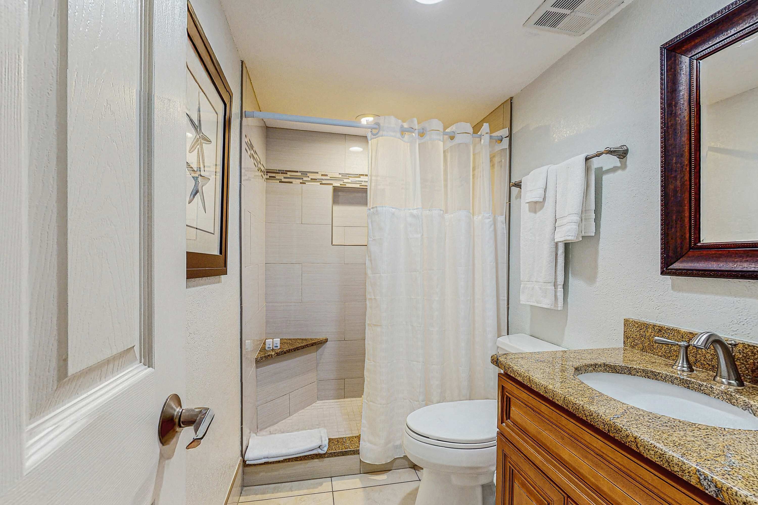 Un baño con ducha, inodoro, lavamanos y tocador.