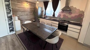 A modern kitchen with a dining area, featuring a wooden wall, hexagonal tiles, and pendant lighting. - Villagrey Residence Tunari (Tunari)