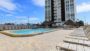 A swimming pool with lounge chairs and a tall building in the background.