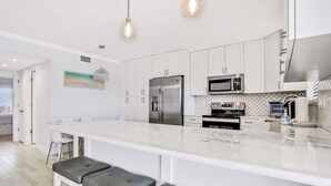 Een moderne keuken met witte kasten, roestvrijstalen apparatuur en een marmeren aanrecht.