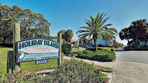Bord Holiday Island met een fraai uitzicht op een strand en palmbomen.
