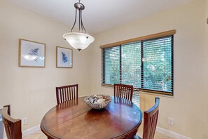 Comedor con una mesa redonda de madera, sillas, un cuenco decorativo y dos cuadros en la pared.