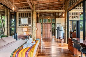 A wooden room with a bed, desk, and large windows.