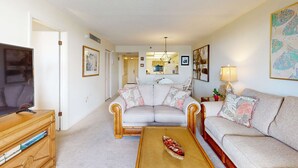 A living room with a sofa, a coffee table, and a television on a wooden stand. - Waterfront condo with pool and spa directly across from wide beach (Indian Shores)