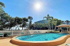 Ein Schwimmbecken mit Holzterrasse, Liegestühlen und einem weißen Zaun.
