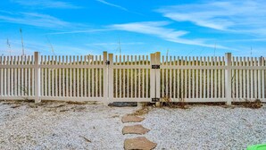 A white picket fence with a gravel path leading to it. - Charming Gulf front condo w/ balcony full kitchen central AC and WD (Treasure Island)