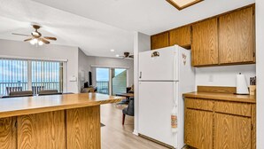 A kitchen with wooden cabinets, a white refrigerator, and a wooden island. - Charming Gulf front condo w/ balcony full kitchen central AC and WD (Treasure Island)