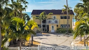 A two-story building with a balcony, surrounded by palm trees and a clear view of the ocean. - Spacious and family friendly with pool dock and just steps to the beaches (Indian Shores)