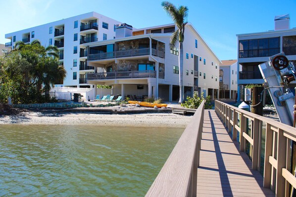 A waterfront hotel with multiple balconies, a wooden deck, and a kayak on the beach. - Spacious and family friendly with pool dock and just steps to the beaches (Indian Shores)