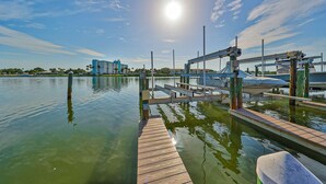 A marina with a wooden dock extending into calm water, surrounded by buildings and a clear sky. - Spacious and family friendly with pool dock and just steps to the beaches (Indian Shores)