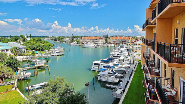 A marina with boats docked, a clear sky, and buildings with balconies.
