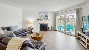 Un salon moderne avec un canapé en cuir, une table basse en bois, une cheminée et une grande fenêtre donnant sur l’extérieur.