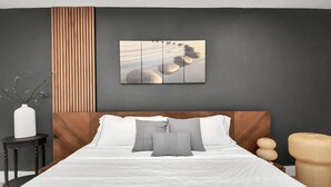 Una camera da letto moderna con un letto grande, una testiera in legno, un quadro appeso al muro e un tavolino con un vaso.
