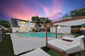 Ein Garten mit Swimmingpool, überdachter Terrasse und umzäunter Fläche.