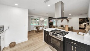 Una cucina moderna con forno integrato, un'area pranzo con tavolo e sedie, e vista su una piscina.