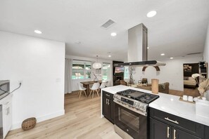 A modern kitchen with a built-in oven, a dining area with a table and chairs, and a view of a pool.