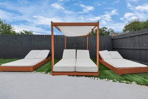 A wooden outdoor seating area with three lounge chairs and a canopy.