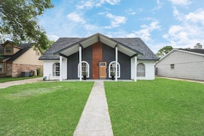 A modern two-story house with a front porch, a central wooden door, and a small attached garage.