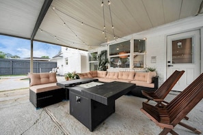 An outdoor patio with a sectional sofa, a coffee table, and a wooden chair.